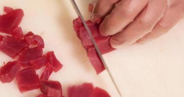 Chef Cutting Tuna Meat In Small Pieces Using Knife On Chopping Board. - high angle shot video