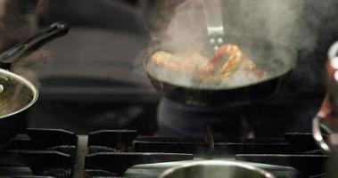 chef lanzando una sartén con gambas en la cocina de un restaurante. - tiro medio video