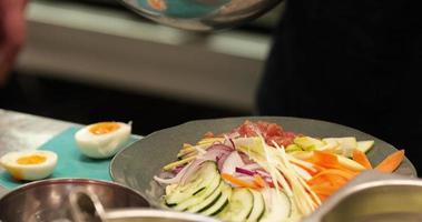 chef preparando uma saudável salada asiática com carne de atum na cozinha. - tiro de perto video