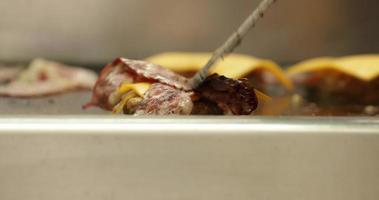 Chef Grilling Hamburger Patty With Slices Of Cheese And Grilled Bacons. - close up shot video