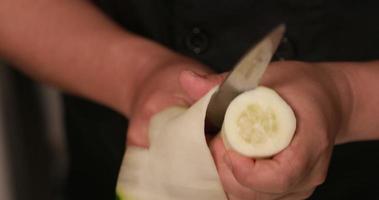 un chef qualifié coupe finement le concombre avec un couteau pour des rouleaux de sushi japonais traditionnels. - photo en gros plan video