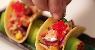 Küchenchef garniert Sushi-Tacos vor dem Servieren mit frisch gehacktem Frühlingszwiebel-Schnittlauch. - Selektiver Fokus