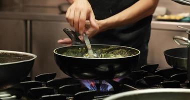 chef cuisinant une sauce crémeuse à feu moyen dans la cuisine d'un restaurant. - photo en gros plan video