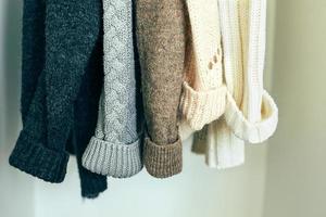 Knitted clothes sweater hanging in the closet. Cozy autumn-winter wardrobe photo