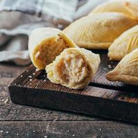 postre nacional de azerbaiyán. postre de pastelería dulce oriental - shekerbura sobre tabla de madera sobre fondo de mesa de madera. primer plano, imagen cuadrada foto