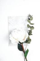 Notebook, flowers white peony and sprig of eucalyptus on white background. Cozy, still life, minimal concept. Top view, flat lay, copy space photo