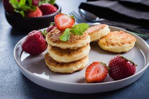 tortitas de requesón con fresa sobre mesa de hormigón. concepto de desayuno. vista superior, espacio de copia foto