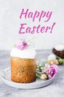 Easter cake kulich. Traditional Easter sweet bread decorated meringue and pink roses on plate on gray stone table background. Copy space. photo