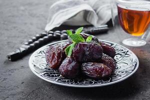 Ramadan kareem. Ramadan Food Concept. Fresh Dates and nuts with rosery on dark concrete background photo
