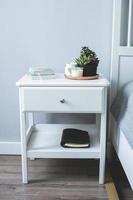 Tiny succulents, candles and black notebook on bedside table in the bedroom in scandinavian style photo