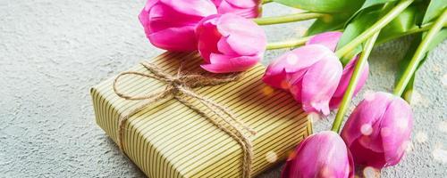 Beautiful tulips with gift box. Happy mothers day, romantic still life on concrete background photo