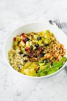 Concept of healthy food. Salad lunch bowl with mix salad, chicken breast, apple, pineapple, raising, dates, brown rice and walnut. Keto salad in bowl on marble background. photo