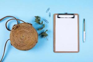 Flat lay composition with rattan bag, eucalyptus and empty clipboard. Top view, copy spase. Mockup concept. photo