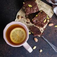 Tea with lemon and mint leaf with homemade biscuit brownie with pistachios for Breakfast on stone table background. Close-up, top view. copy space photo