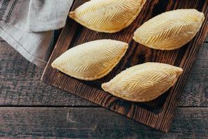 postre nacional de azerbaiyán. postre de pastelería dulce oriental - shekerbura sobre tabla de madera sobre fondo de mesa de madera. vista superior, espacio de copia foto