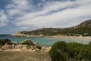 A turquoise blue sea and white sand beach with rocks in Sardinia Italy photo