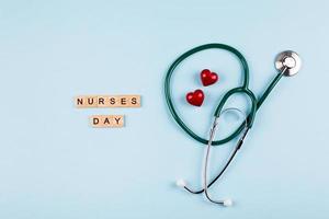 fondo de vacaciones del día nacional de la enfermera. estetoscopio médico, dos corazones rojos y texto con letras de madera. foto