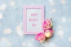 Mother's Day Card. Photo frame with greeting text and pink roses on blue background. Top view, flat lay