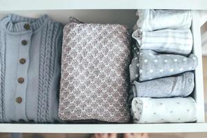 Baby or newborn things of white, blue, grey colors in drawer. Lady fly system, kondo konmary concept photo