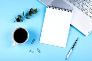 Flat lay office workspace with empty open notebook, eucalyptus, cup of coffee. Top view. copy space. Mockup concept photo
