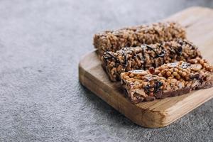 Healthy snack. Granola bar. Cereal granola bar with nuts, chocolate on wooden board. Concrete table background. Copy space photo