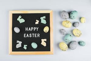 Easter Card Flat Lay Concept. Greeting board with text Happy Easter and pastel colorful eggs, wooden bunny. Top view. photo