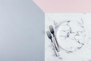Empty ceramic marble plate and cutlery on tricolor pink gray marble background. Copy space. photo