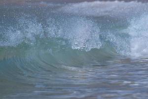 una ola rompiendo en la orilla de arena foto