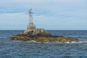 abandoned lighthouse on small rocks island photo