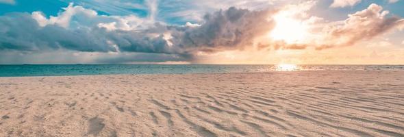 primer plano de la arena en la playa y el cielo azul de verano. paisaje de playa panorámica. playa tropical vacía y paisaje marino. cielo anaranjado y dorado del atardecer, arena suave, tranquilidad, luz del sol tranquila y relajante, humor de verano foto