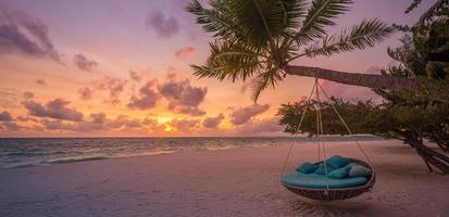 Tropical sunset beach background as summer landscape panorama, beach swing or hammock and white sand and calm sea beach banner. Perfect beach scene vacation or summer holiday panorama photo