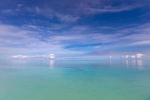 Blue sky over sea or ocean water surface. Idyllic sea and sky template. Tropical beach landscape and seascape, inspirational, tranquil, and relaxing sea view. Horizon, clouds and soft waves photo