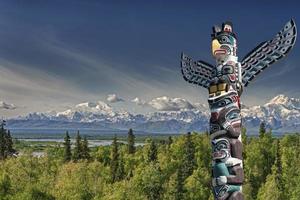 A totem wood pole in mountain background photo