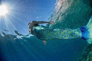 sirena nadando bajo el agua en el mar azul profundo foto