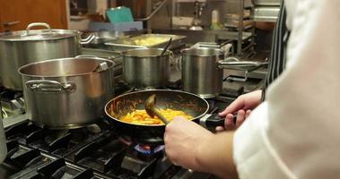 El chef del restaurante lanza pasta penne que se está cocinando en la cocina: cierre, cámara lenta video