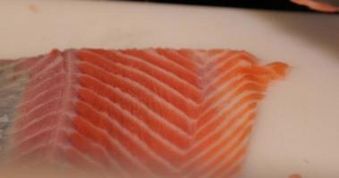 esperto capocuoco Rifinitura il carne di un' fresco salmone filetto utilizzando un' coltello per Sushi piatto. - vicino su tiro video