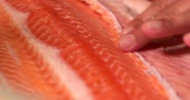 itamae capocuoco con un' grande taglio abilità affettare sottilmente il carne di un' salmone pesce per Sushi piatto. - vicino su tiro video