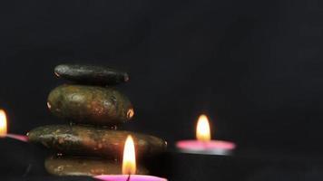 massage stones with burning candles in close up view used in relaxing time and yoga. video