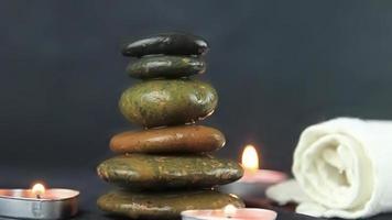 massage stones with burning candles in close up view used in relaxing time and yoga. video