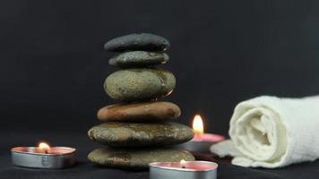 massage stones with burning candles in close up view used in relaxing time and yoga. video
