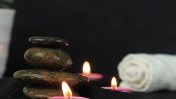 massage stones with burning candles in close up view used in relaxing time and yoga. video