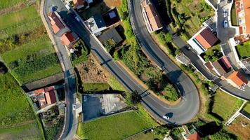 vehículos circulando por carreteras curvas a través de casas y campos. rotación aérea de arriba hacia abajo video
