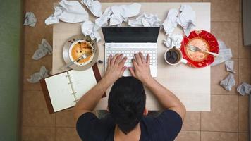 Male Freelancer Working on Laptop at Home in Clutter and Chaos. Mess at the Desk. Man Works Remotely Among the Garbage in a Bachelor Apartment. Top View video