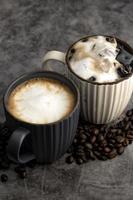 café con leche caliente y café con leche helado con granos de café sobre fondo de hormigón. foto