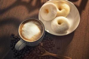 Hot latte and donuts on wooden table behind window photo