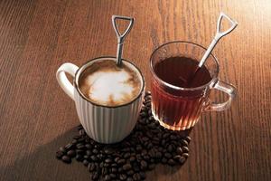 Hot coffee with coffee beans and hot tea on wooden background. photo