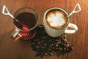 café caliente con granos de café y té caliente sobre fondo de madera.