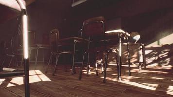 View to classroom with tables and small blackboard and grungy walls photo