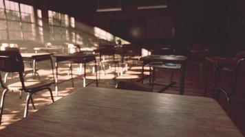 View to classroom with tables and small blackboard and grungy walls photo