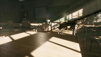 View to classroom with tables and small blackboard and grungy walls photo